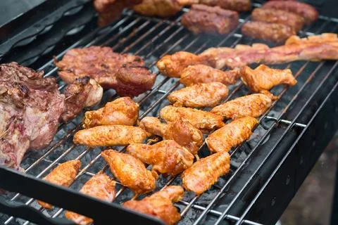 Close-up of assorted meat and chicken wings grilling on hot charcoal barbec.. Stock Photos