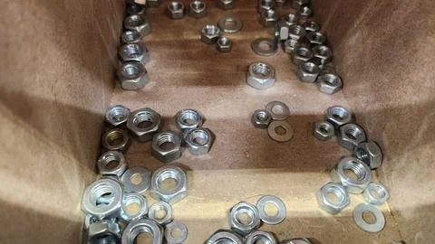 Close-up of assorted metal nuts and washers in a container, perfect for eng.. 写真素材