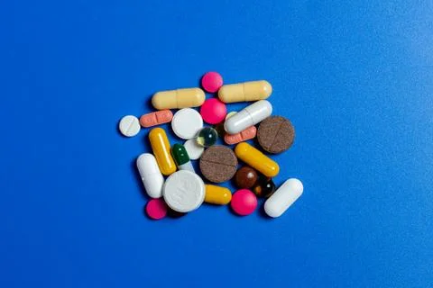 Close-up of assorted multi-colored pills on a blue plane. Medical flat lay. I 写真素材