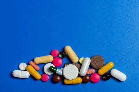 Close-up of assorted multi-colored pills on a blue plane. Medical flat lay. I Stock Photos