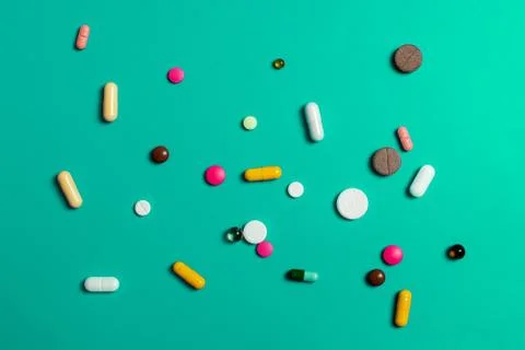 Close-up of assorted multi-colored pills on a green background. Medical flat  Stock Photos
