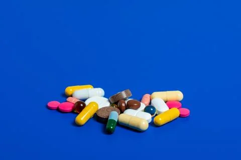 Close-up of assorted multi-colored pills on a blue plane. Medical flat lay. I Stock Photos