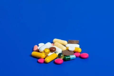 Close-up of assorted multi-colored pills on a blue plane. Medical flat lay. I Stock Photos
