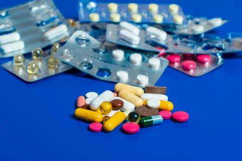 Close-up of assorted multi-colored pills on a blue background. Medical flat l Stock Photos