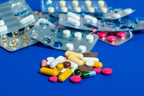 Close-up of assorted multi-colored pills on a blue background. Medical flat l Stock Photos