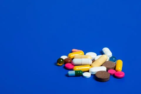 Close-up of assorted multi-colored pills on a blue plane. Medical flat lay. I Stock Photos
