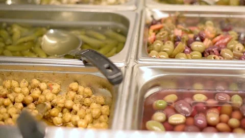 Close-up of assorted olives, pickles, and other items in a grocery store salad Видео 277617318