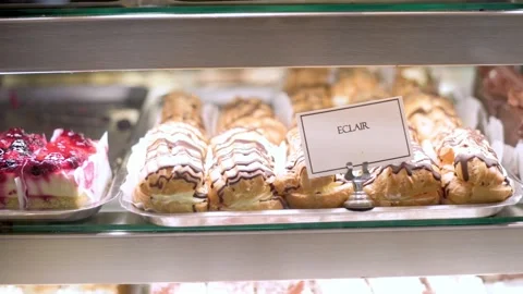 Close-up of assorted pastries, including lemon Bavarian and eclairs, in a bak Vidéo 277559448