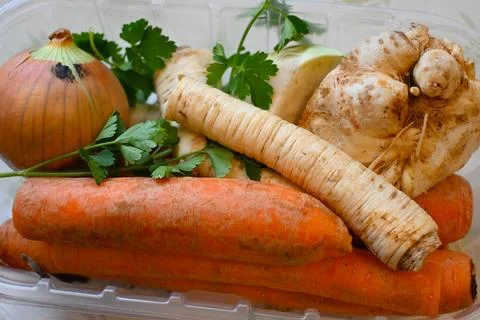 A close-up of assorted root vegetables including carrots, parsnip, onion, and Фото