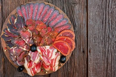 Close up of assorted sliced dry-cured meat on the wooden plate background Foto stock