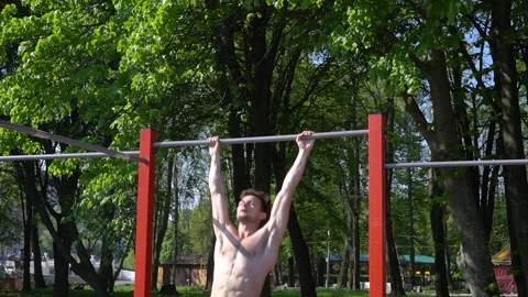 Close up of athlete man working out with horizontal bar outdoor. Portrait of Video stock 130348372