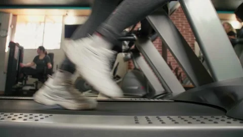 Close-up athletic legs run on a treadmill in a fitness room. Side view of white  Stock Footage 230508051