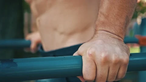 Close-up of athletic man doing hard intense exercises pull ups on parallel bars Stock Footage 148970174