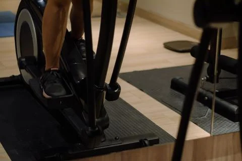 Close-up of athletic person's legs exercising on an elliptical m Stock Photos