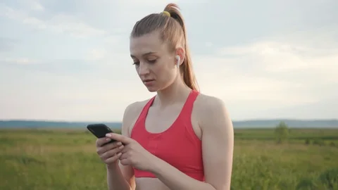 Close up athletic woman in training use phone in road field sunset outdoors Stock Footage 112744853