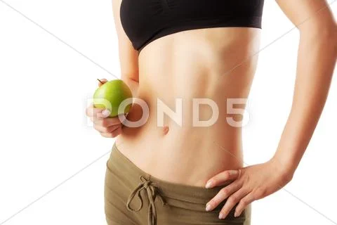 Close up of athletic womans belly holding a green apple in hand. Stock Photos