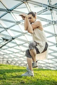 Close up of attractive athletic man practicing yoga and warming up outdoors. Stock Photos