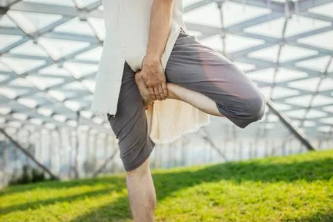Close up of attractive athletic man practicing yoga and warming up outdoors. Stock Photos
