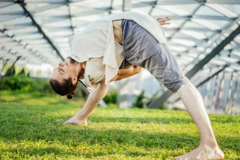 Close up of attractive athletic man practicing yoga and warming up outdoors. Stock Photos