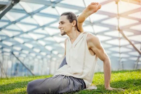 Close up of attractive athletic man practicing yoga and warming up outdoors. Stock Photos