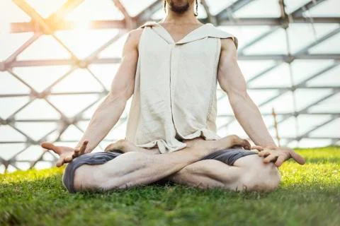 Close up of attractive athletic man practicing yoga and meditating outdoors. Stock Photos