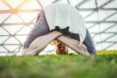 Close up of attractive athletic man practicing yoga and warming up outdoors. Stock Photos
