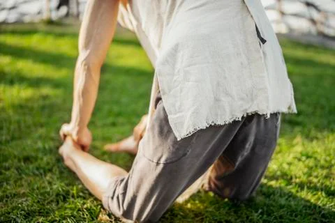 Close up of attractive athletic man practicing yoga and warming up outdoors. Stock Photos