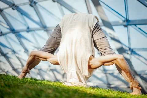 Close up of attractive athletic man practicing yoga and warming up outdoors. Stock Photos