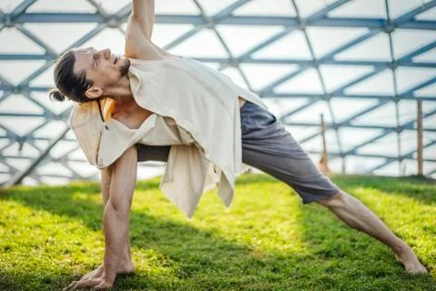 Close up of attractive athletic man practicing yoga and meditating outdoors. Stock Photos