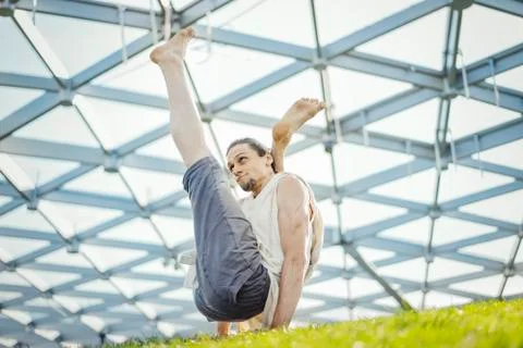 Close up of attractive athletic man practicing yoga and warming up outdoors. Stock Photos