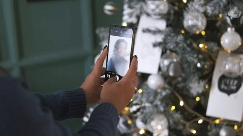 Close up of attractive brunette taking selfie on cellphone over christmas tree Video stock 119199310