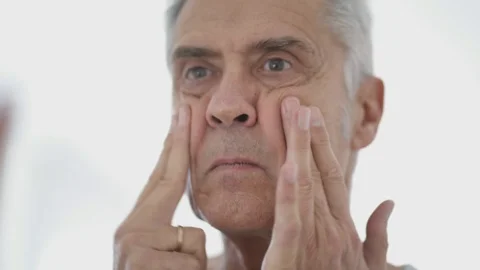 Close up of attractive senior man applying face cream in mirror Video stock 99767551