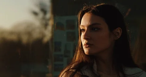 Close-up of attractive woman's face looking far away in the rays of evening sun Stock Footage 106464725