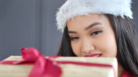 Close-up attractive young Asian Christmas girl wearing Santa Claus hat holding Видео 99487853