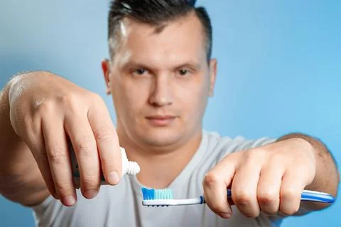 Close up of an attractive young man brushing his teeth. A man squeezes toothp Stock Photos