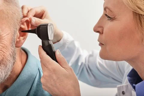 Close-up of audiologist checking elderly man ear with an otoscope during a he Foto stock