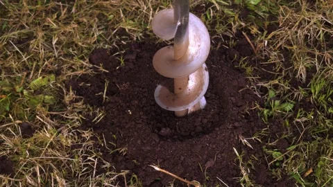 Close-up of auger drill bit entering soil to create hole for hedge planting Stock Footage 307837812