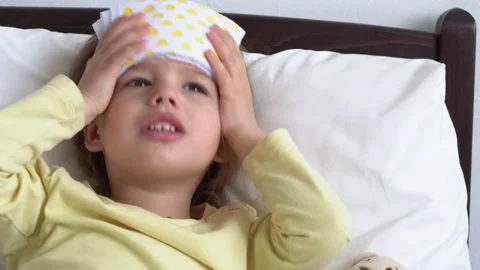 Close up Authentic cute little sick preschool child girl puts compress on Stock Footage 152422503
