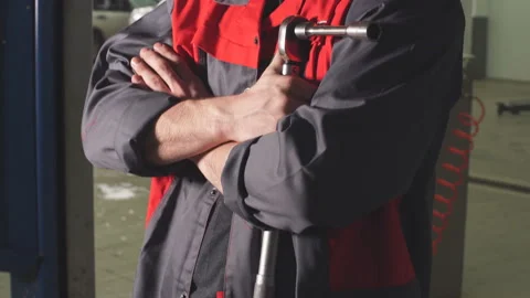 Close-up auto mechanic crossed hands and looking at camera while standing under Stock Footage 89708280