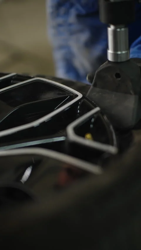 Close-up of an auto mechanic using a tire changing machine to mount a tire on a Видео 334180169