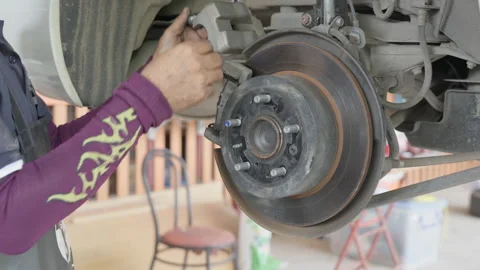 Close up of a auto mechanic's hands removing the break shoes off Stock Footage 239741976