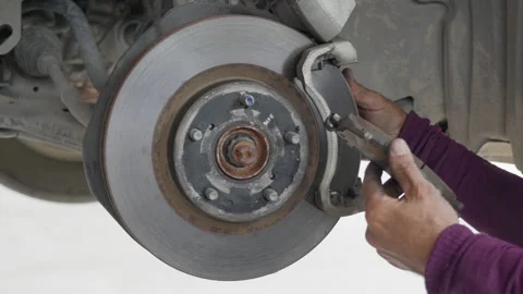 Close up of a auto mechanic's hands removing the break shoes off Stock Footage 239742792
