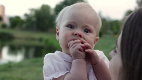 Close-up of a baby with blue eyes exploring food outdoors near water Stockbeeldmateriaal 342494862