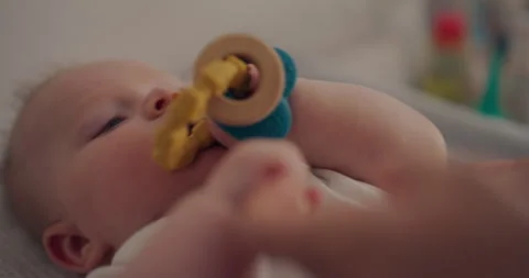 Close-up of Baby Boy Chewing Teether on Changing Table Stock Footage 317784377