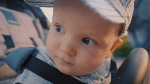 Close-up: baby boy sitting in a stroller on the street on a summer day, playing Stock Footage 110858770