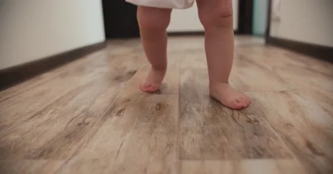 Close-up of baby boy walking his first steps,slow motion Stock Footage