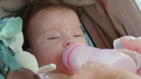 Close-up of a baby drinking from a bottle in a stroller Stock Footage 344897640