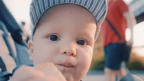 Close-up: baby eating bread while sitting in a stroller outside on a summer day Stock Footage 110858993