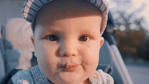 Close-up: baby eating bread while sitting in a stroller outside on a summer day Stock Footage 110858998