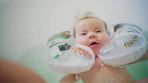 Close up of baby floating in bath support in bathtub with water reflections 스톡 동영상 331054688
